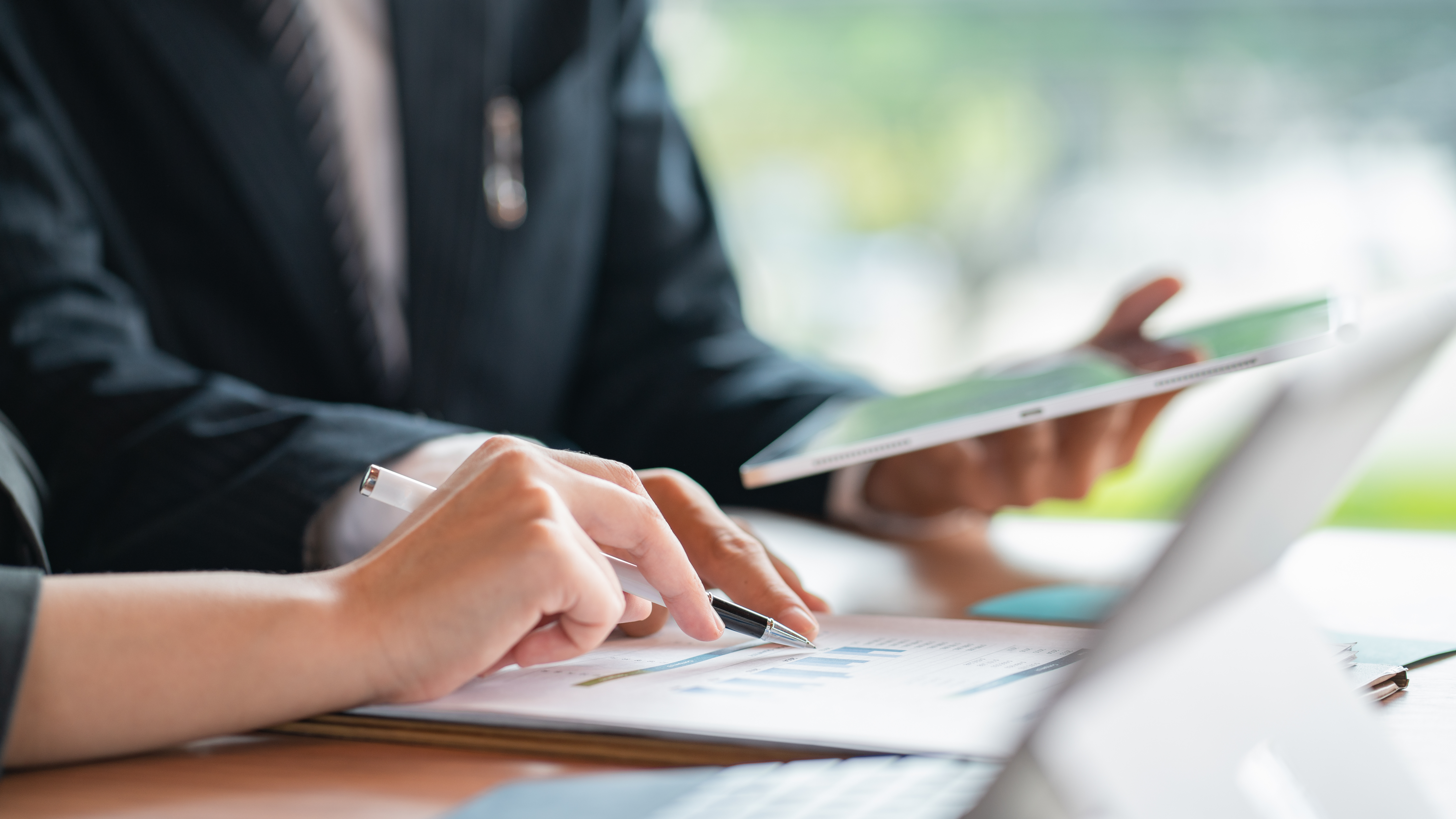working professional typing on laptop holding ipad