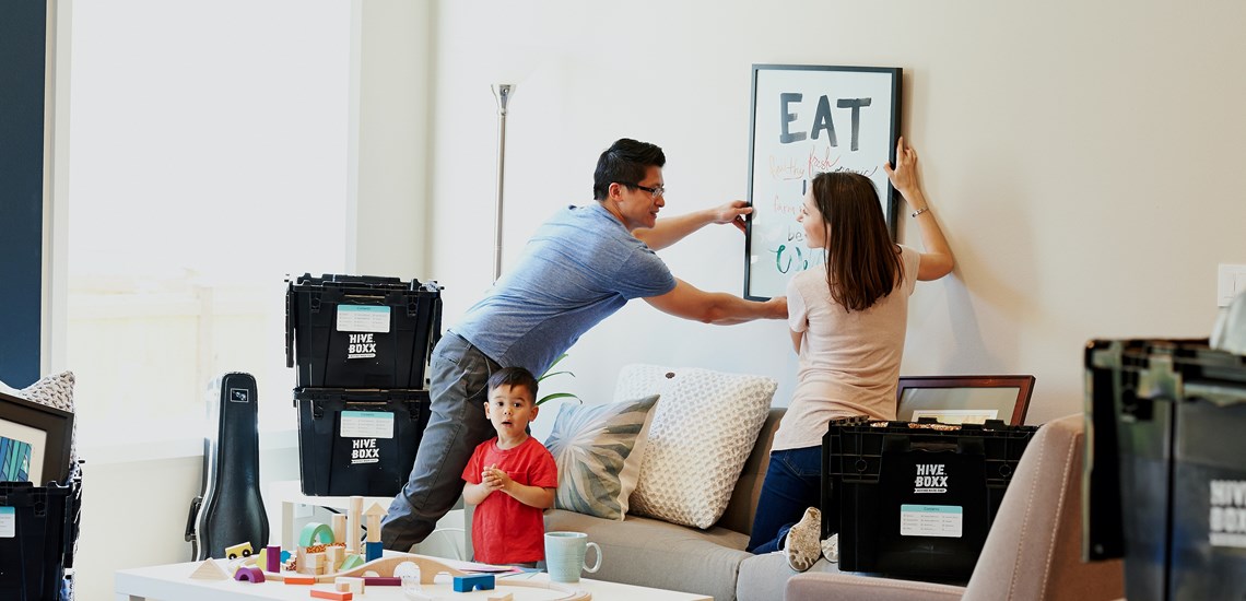 couple mounting artwork in frame on to wall
