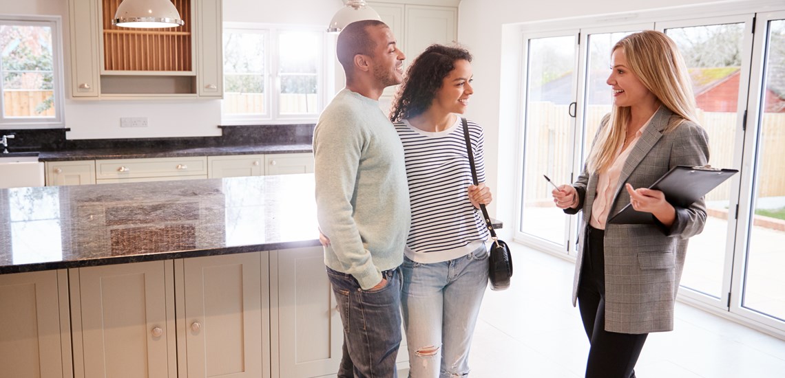 Couple talking to estate agent during house viewing